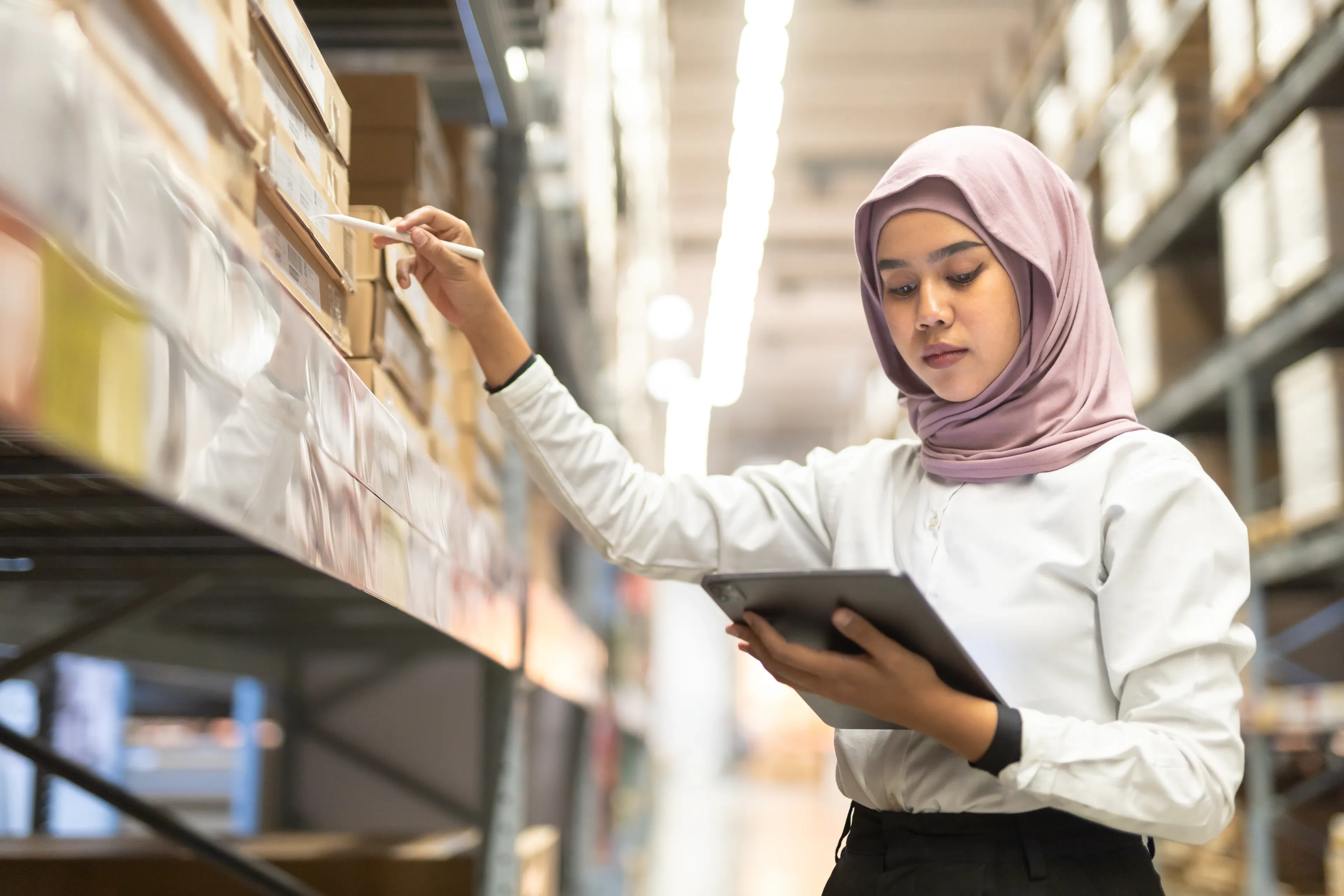 Eine muslimische Frau benutzt ein Tablet in einem Lagerhaus